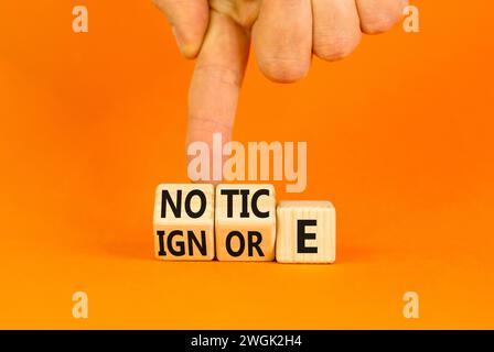 Symbol beachten oder ignorieren. Konzeptwort Hinweis oder Ignorieren auf Holzwürfeln. Schöner oranger Tisch mit orangefarbenem Hintergrund. Geschäftsmann Hand. Business Lifestyle Stockfoto