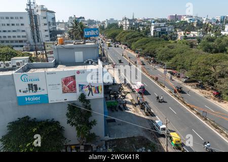 Hassan, Karnataka, Indien - 10. Januar 2023: Eine Luftaufnahme fängt die dynamische urbane Umgebung einer Stadt mit Verkehrsfluss und Werbung für Billboar ein Stockfoto