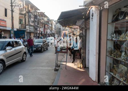 Hassan, Karnataka, Indien - 10. Januar 2023: Eine geschäftige Straße in Hassan, Karnataka, wird lebendig mit dem Trubel von Autos, Fußgängern und Ladenbesitzern Stockfoto