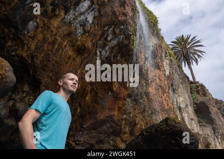 Mann, der unter dem Wasserfall auf Teneriffa, Kanarische Insel, Spanien steht. Stockfoto