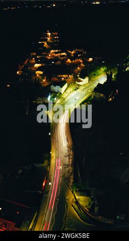 Nächtlicher Blick auf eine kurvige Straße mit Lichtwegen, die ein beleuchtetes Stadtgebiet in Knaresborough, North Yorkshire, verbinden Stockfoto