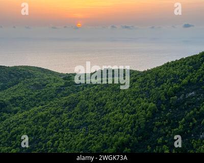 Pinien bei Sonnenuntergang, Olivenhaine und Meerblick auf einer griechischen Insel. Mediterraner Sonnenuntergang vom Aussichtspunkt Agalas. Sitzen und den Sonnenuntergang in Zakynth beobachten Stockfoto