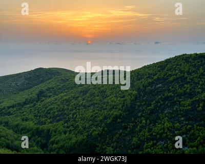 Pinien bei Sonnenuntergang, Olivenhaine und Meerblick auf einer griechischen Insel. Mediterraner Sonnenuntergang vom Aussichtspunkt Agalas. Sitzen und den Sonnenuntergang in Zakynth beobachten Stockfoto