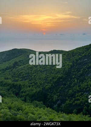 Pinien bei Sonnenuntergang, Olivenhaine und Meerblick auf einer griechischen Insel. Mediterraner Sonnenuntergang vom Aussichtspunkt Agalas. Sitzen und den Sonnenuntergang in Zakynth beobachten Stockfoto