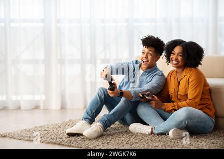 Ein fröhliches junges Paar genießt einen verspielten Moment zusammen, während es auf dem Boden sitzt Stockfoto