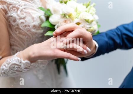 Der Bräutigam legt der Braut einen Ehering an den Finger. Stockfoto