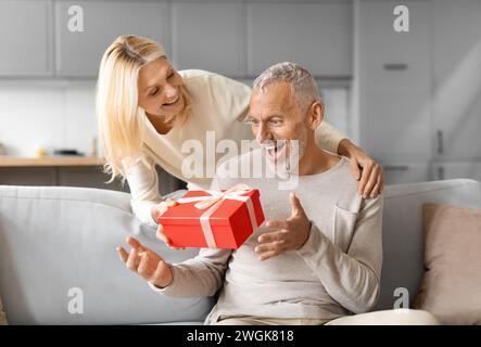 Liebevolle reife Frau, die ihren Mann mit Valentinstag begrüßt Stockfoto