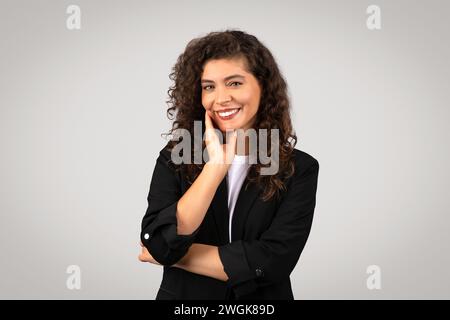 Freundliche Frau, die mit Hand auf Wange lächelt Stockfoto
