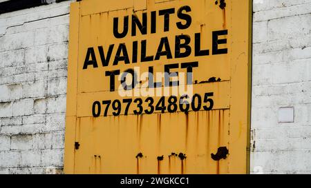 Barry, Vale of Glamorgan, Wales 02. Februar 2024: Eine leere Industrieeinheit zu vermieten, Ein großes Schild mit schwarzen Buchstaben an einer hellgelben Tür. Stockfoto