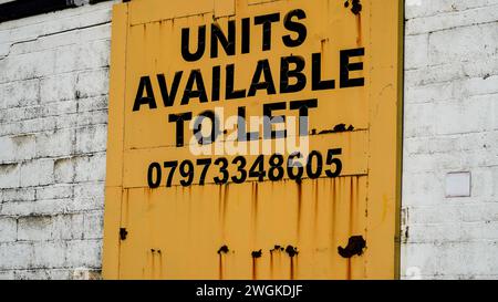 Barry, Vale of Glamorgan, Wales 02. Februar 2024: Eine leere Industrieeinheit zu vermieten, Ein großes Schild mit schwarzen Buchstaben an einer hellgelben Tür. Stockfoto