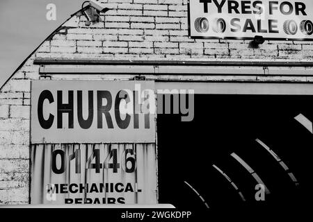 Barry, Vale of Glamorgan, Wales 02. Februar 2024: Reifenverkauf und -Montage werden in einer bogenförmigen Vintage-Industrieeinheit auf dem Dockland beworben. Schmutzige weiße Ziegelwand Stockfoto