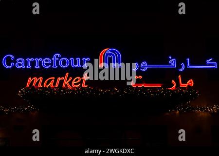 Dubai, VAE, 10.10.21. Carrefour Market beleuchtetes Logo mit arabischem Markennamen und Weihnachtsbeleuchtung auf schwarzem Hintergrund, Dubai, Vereinigte Arabische Emirate Stockfoto