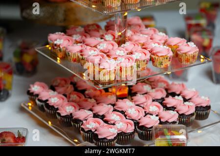 Geburtstagskuchen auf dreistufigem Glas-Ausstellungsstand festliche rosa weiße Blume aus nächster Nähe Stockfoto