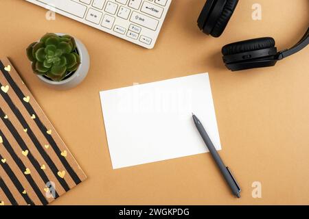 Desktop mit leerer Karte, Notizblock, Computertastatur, saftiger Pflanze, Stift und Kopfhörern auf braunem Tisch. Draufsicht, flach, Modell. Stockfoto