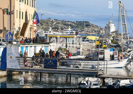 Leute, die an einem sonnigen Wintertag in Sanremo, Imperia, Ligurien, Italien anlegten, um frittierten Fisch von einem Frittierboot zu kaufen Stockfoto