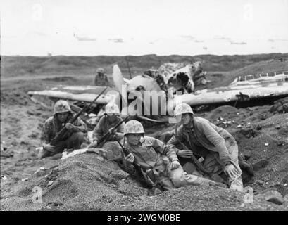 First Lieutenant Arthur Carley aus Ohio findet Zuflucht für seinen Zug in der Nähe eines zerstörten Zero auf dem Motoyama Airfield. Iwo Jima, Japan. 23. Februar 1945. Kompanie E, 2. Bataillon, 23. Marine-Regiment, 4. Marine-Division. Stockfoto