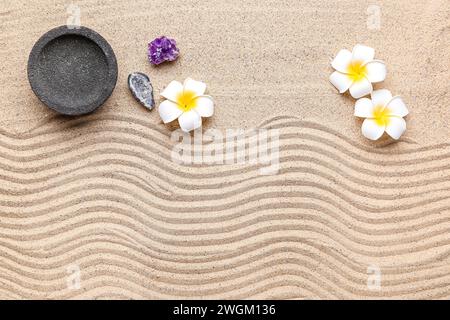 Schüssel, Kristalle und Plumerieblumen auf Sand mit Linien. Zen-Konzept Stockfoto