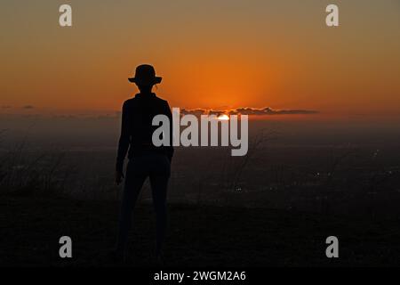 Silhouette einer aktiven Frau, die den Sonnenuntergang beobachtet Stockfoto