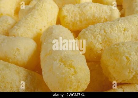 Nahaufnahme der gelben Luftmais-Sticks Nahaufnahme. Knusprige Maissnacks-Textur. Selektiver Fokus. Stockfoto