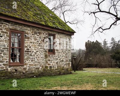 Altes Steinhaus mit moosigem Dach und knorrigem Baumzweig in der historischen Stadt Virginia. Stockfoto