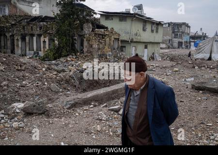 Hatay, Türkei. Februar 2024. Ein alter Mann geht nachdenklich durch die Ruinen. Am 6. Februar 2023 ereignete sich in der Südtürkei ein Erdbeben der Stärke 7,8, dem kurz nach Mittag ein weiteres Erdbeben der Stärke 7,5 folgte. Mehr als 50.000 Menschen kamen bei dem Erdbeben ums Leben, das in 11 Städten der Türkei große Zerstörungen angerichtet hat. Quelle: SOPA Images Limited/Alamy Live News Stockfoto