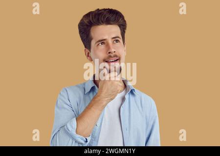 Junger, gutaussehender, lächelnder Mann mit zweifelhaftem, nachdenklichem Ausdruck. Stockfoto