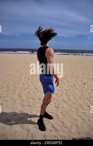 Junger, gutaussehender Mann, der an einem Sandstrand steht Stockfoto
