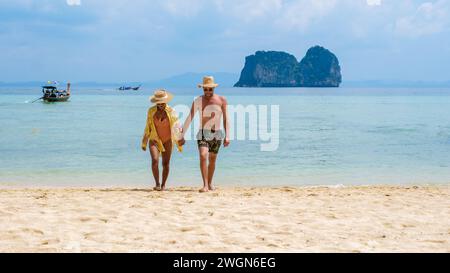 Ein paar Thai-Frauen und europäische Männer am Strand der tropischen Insel Koh Ngai Thailand, mit weichem weißem Sand und einem türkisfarbenen Ozean in Koh Ngai Trang Thailand Stockfoto