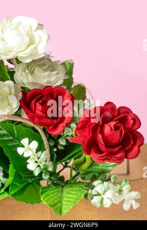 Ein Blumenstrauß aus roten und weißen Rosen in der Papierkarton auf rosa Hintergrund. Stockfoto