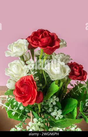 Ein Blumenstrauß aus roten, weißen und rosa Rosen auf rosa Hintergrund. Stockfoto