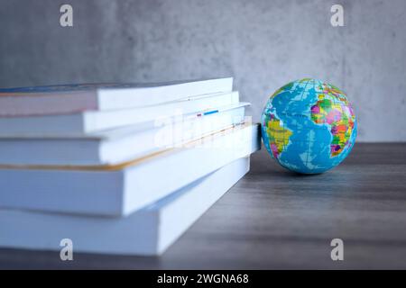 Großbildstapel mit Büchern mit einer Kugel auf einem Holztisch. Kopierbereich für Text. Weltbuchtag, Bildung und Wissenskonzept. Stockfoto