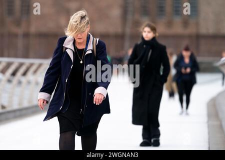 Menschen trotzen dem Wetter, wenn sie die Millennium Bridge in London überqueren. Ein starkes Schneeband könnte später in dieser Woche zu Störungen führen, wobei in höheren Gebieten bis zu 20 cm möglich sind. Bilddatum: Dienstag, 6. Februar 2024. Stockfoto