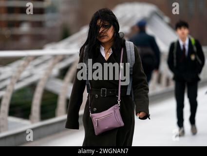 Menschen trotzen dem Wetter, wenn sie die Millennium Bridge in London überqueren. Ein starkes Schneeband könnte später in dieser Woche zu Störungen führen, wobei in höheren Gebieten bis zu 20 cm möglich sind. Bilddatum: Dienstag, 6. Februar 2024. Stockfoto