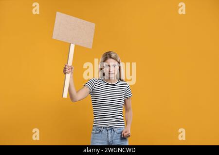 Frau mit leerem Schild auf orangem Hintergrund, Platz für Text Stockfoto