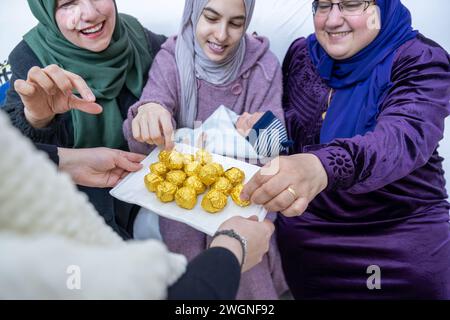 Frauen, die Süßigkeiten zusammen haben und sich aufgeregt fühlen, Gastfreundschaft-Konzept für muslimische Frauen Stockfoto