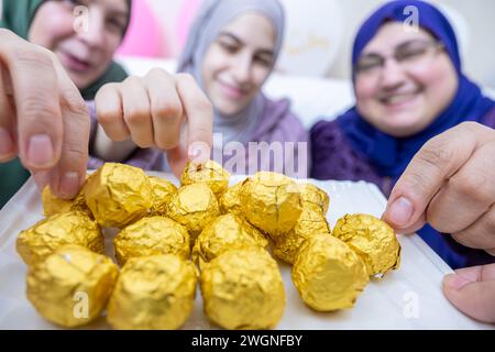 Frauen, die Süßigkeiten zusammen haben und sich aufgeregt fühlen, Gastfreundschaft-Konzept für muslimische Frauen Stockfoto