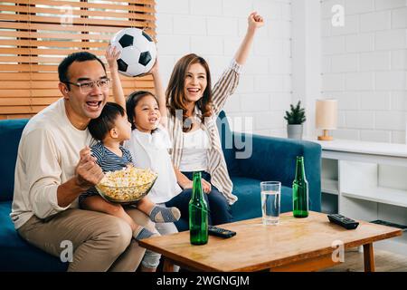Eine glückliche Familie genießt den Nervenkitzel eines Fußballspiels zu Hause Stockfoto