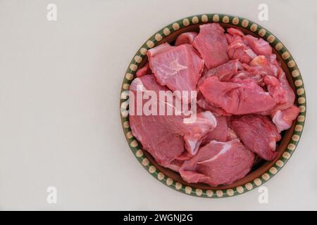 Fleischstücke auf einem rustikalen Gericht auf beigefarbenem Hintergrund. Rohes Rindfleisch zum Kochen. Draufsicht. Stockfoto