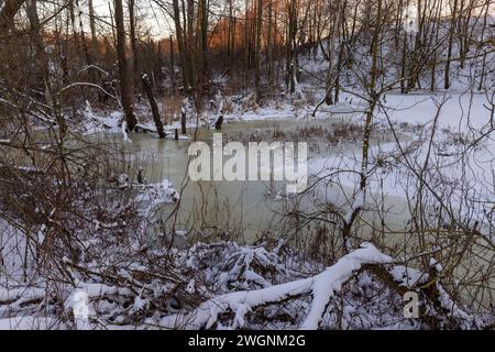 Eisbedecktes Wasser in einem Fluss im Winter, Sonnenuntergang auf einem Fluss, dessen Ufer mit Eis bedeckt sind Stockfoto