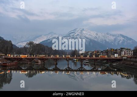 Pendler spazieren an einem kalten Winterabend in Srinagar entlang der hölzernen Fußbrücke. Das Wetter im Kaschmir-Tal hat sich verbessert, nachdem es nach längerem Trockentewetter erneut Schneefall bekommen hat. Der Flugbetrieb am Flughafen Srinagar und der Straßenverkehr auf der Autobahn Srinagar-Jammu, die am Sonntag vom Schneefall betroffen waren, wurden am Montag wiederhergestellt. (Foto: Saqib Majeed / SOPA Images/SIPA USA) Stockfoto