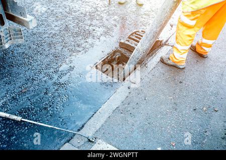 Bauherr reinigt blockierte Straßenrinnen mit Schaufel und Vakuumbagger Stockfoto