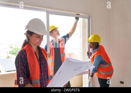 Architekt untersucht Baupläne in der Nähe von Zimmerleuten vor Ort Stockfoto