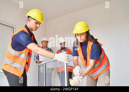 Zimmerleute untersuchen Fensterrahmen in der Nähe von Kollegen Stockfoto