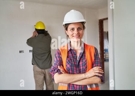 Lächelnde junge Erbauerin mit überkreuzten Armen Stockfoto