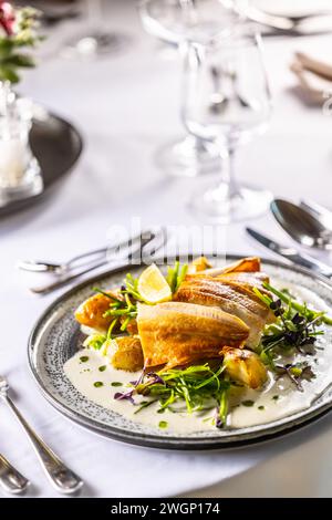 Leicht geräuchertes Forellenfilet, gebackene Kartoffeln, Beurre Blanc Sauce, Lauch und Limettendressing. Kreativ servierter Fisch auf einem Teller im Restaurant. Stockfoto