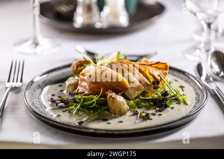 Leicht geräuchertes Forellenfilet, gebackene Kartoffeln, Beurre Blanc Sauce, Lauch und Limettendressing. Kreativ servierter Fisch auf einem Teller im Restaurant. Stockfoto