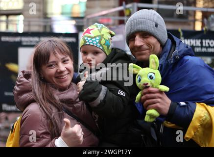 IWANO-FRANKIWSK, UKRAINE - 05. FEBRUAR 2024 - Eine Frau mit einem Kind in den Armen macht ein Foto mit einem Freiwilligen, Blogger und ehemaligen Asow-Regimentssoldaten Petro Skrypka, der von Kiew nach Iwano-Frankiwsk ging, um Geld für die ukrainischen Streitkräfte in Iwano-Frankowsk, Westukraine zu sammeln. Stockfoto