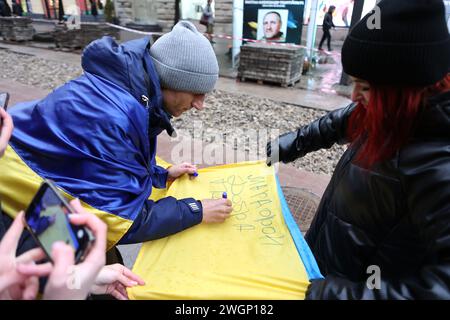 IWANO-FRANKIWSK, UKRAINE - 5. FEBRUAR 2024 - Ein Freiwilliger, Blogger und ehemaliger Asow-Regimentssoldat Petro Skrypka, der von Kiew nach Iwano-Frankiwsk ging, um Geld für die ukrainischen Streitkräfte zu sammeln, hinterlässt eine Inschrift auf einer Flagge der Ukraine, Iwano-Frankowsk, Westukraine. Stockfoto