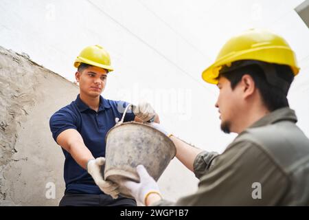 Junge männliche maurerkollegen mit Eimer Stockfoto