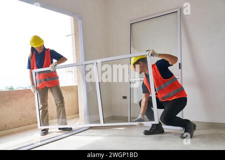 Zimmerleute installieren Fensterrahmen im Haus Stockfoto